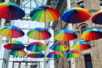 En konstinstallation med färgglada paraplyer upphängda i taket.