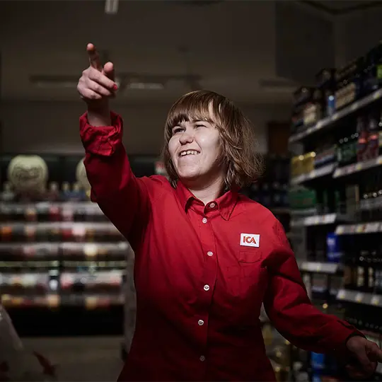 En kvinna med funktionsnedsättning pekar i en ICA-butik.