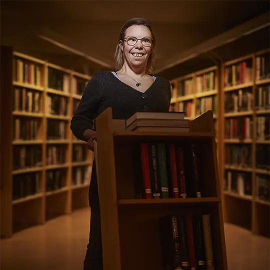 En kvinna med funktionsnedsättning jobbar i ett bibliotek.